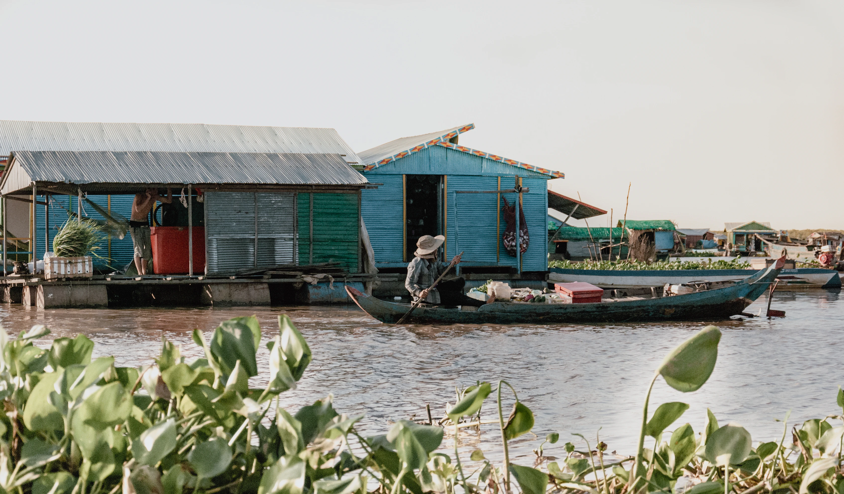 Man paddling boat on a river next to houses